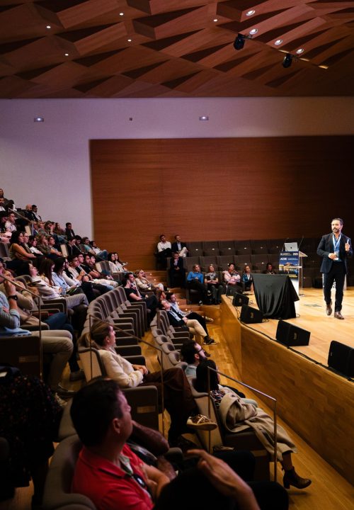 Fotografía de congreso AEDE 2025 - Ponente masculino en escenario con imagen clínica dental en pantalla Alicante