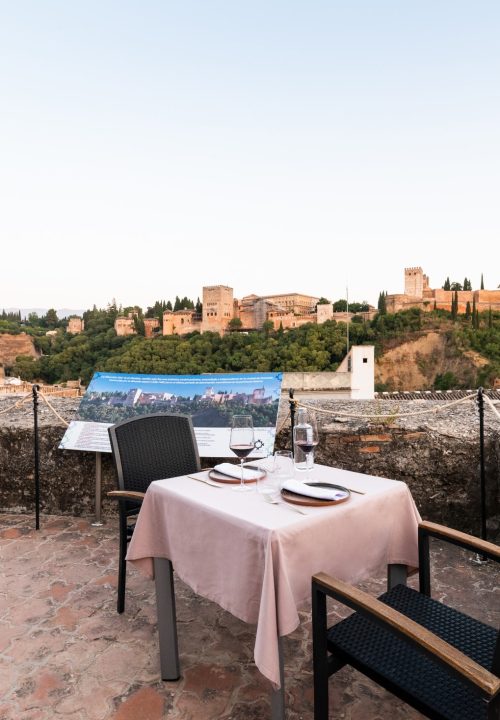 Fotografía de terraza romántica con vistas a la Alhambra - Mesa exterior en restaurante Carmen de Aben Humeya Granada