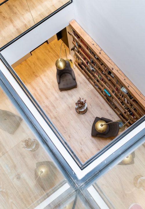 Fotografía de interior de hotel boutique Granada - Zona de biblioteca con suelo de cristal y lámparas doradas