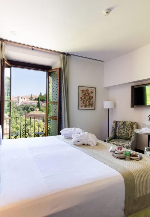 Fotografía de habitación de hotel con vistas a la Alhambra - Cama doble con balcón y decoración nazarí Granada